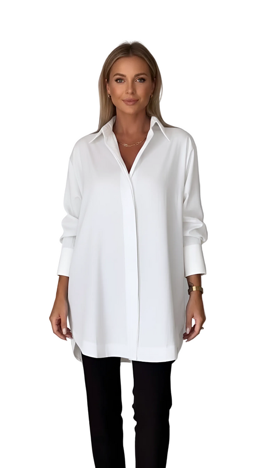 Woman wearing a white long-sleeve shirt and black pants against a plain background